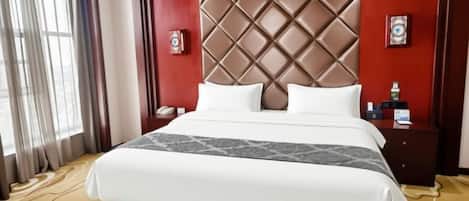 A hotel room with a large bed, a headboard with a diamond pattern, a nightstand with a phone, and a window with curtains.