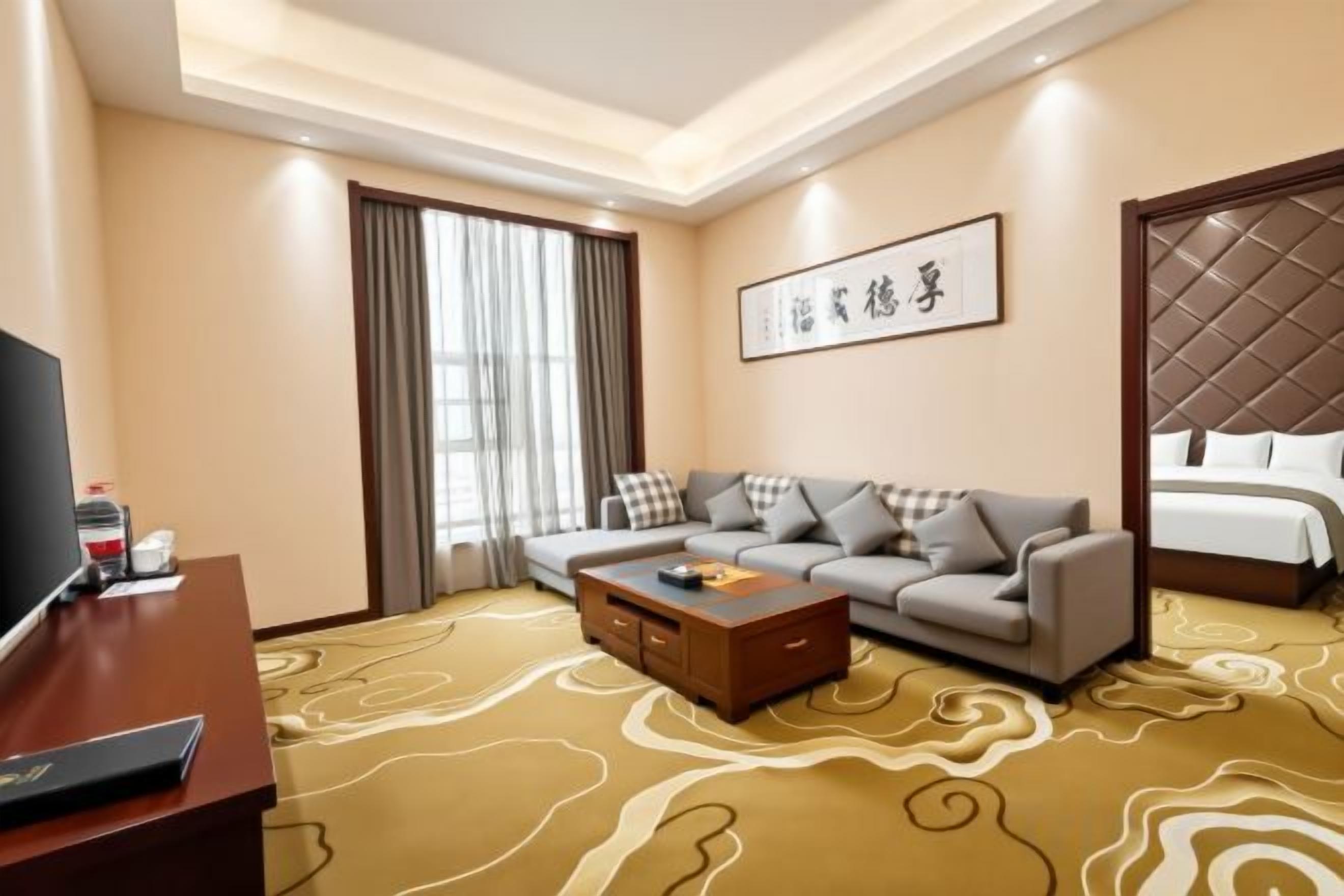 A hotel room with a sofa, a bed, a television, and a coffee table.