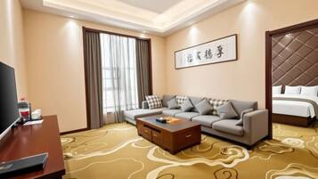 A hotel room with a sofa, a bed, a television, and a coffee table.