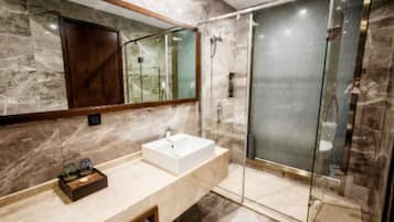 A modern bathroom with a marble vanity, a glass shower enclosure, and a large mirror.