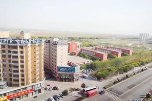 Un edificio de varios pisos con una planta baja comercial, junto a una calle con vehículos estacionados y un autobús.