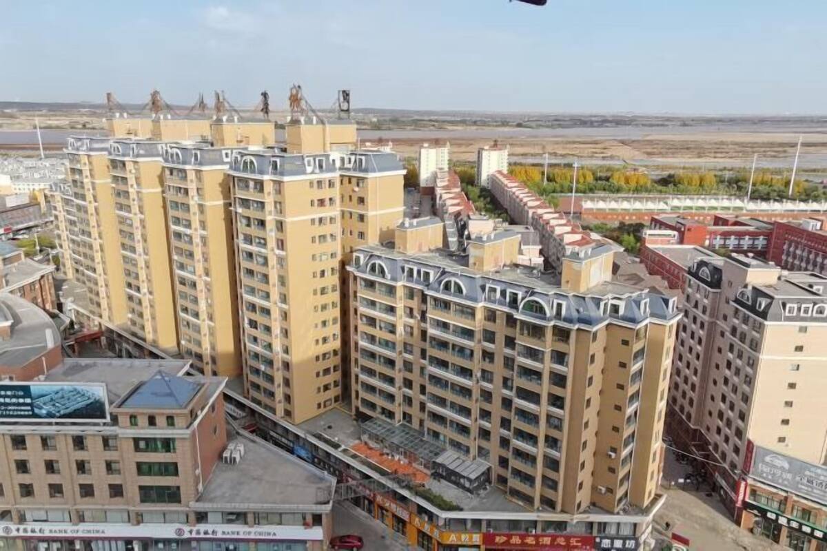 Un edificio de varios pisos con techo plano, ventanas amplias y una planta baja comercial con señalización.