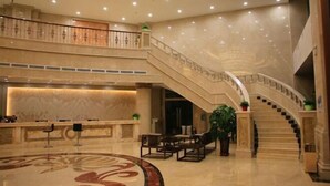 A spacious lobby with a marble reception desk, a grand staircase, and comfortable seating areas. - Shizuishan Jinguan Hotel (Shizuishan)