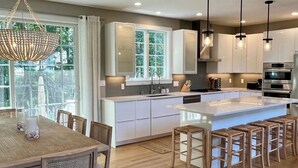 Una cocina moderna con armarios blancos, una isla grande e iluminación colgante.