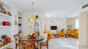 Ein modernes Wohnzimmer mit Essbereich, gelben Sofas und einem Fernseher.