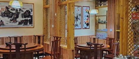 Un interior rústico de madera con mesas y sillas redondas, decoración mural y un separador de celosías.