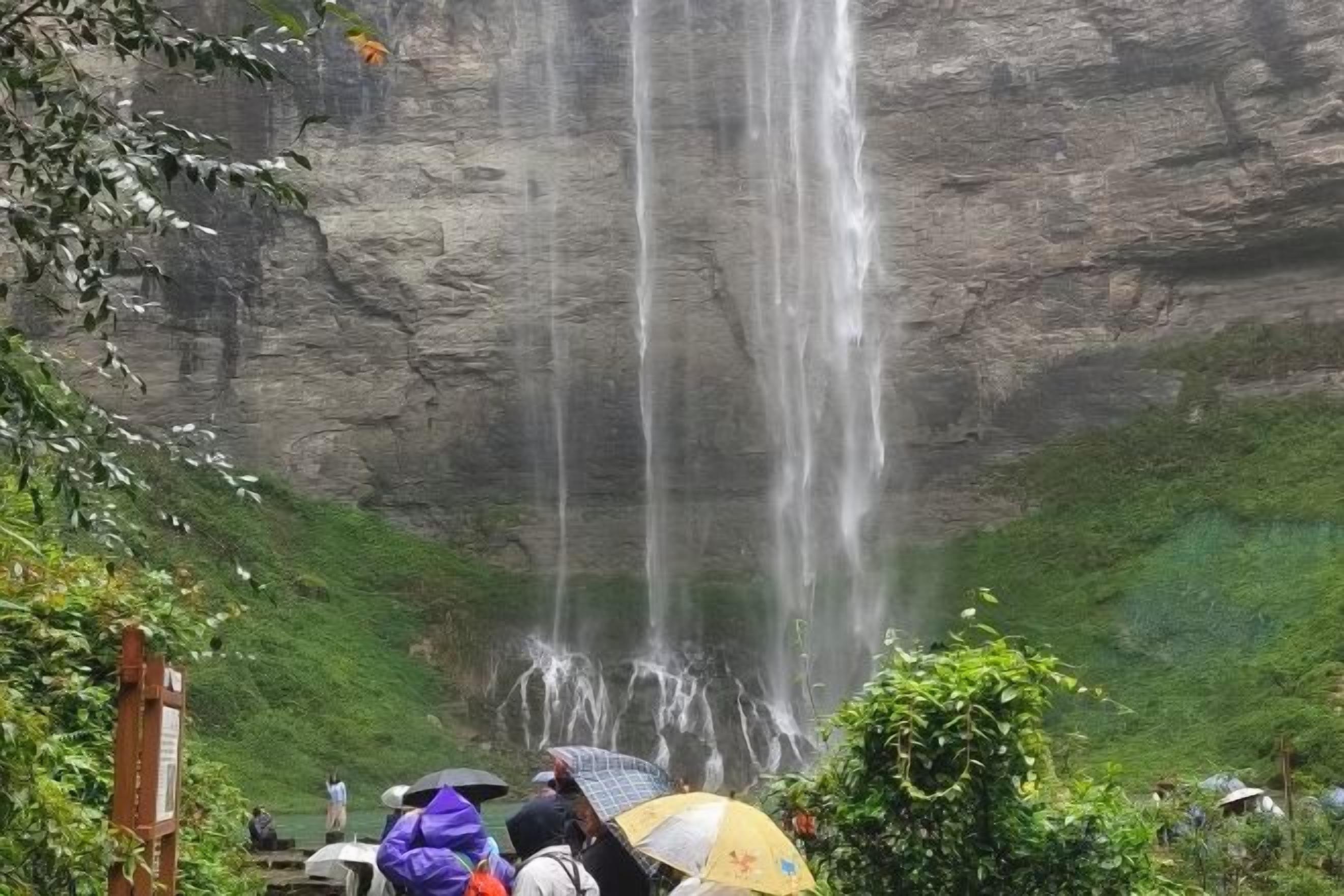 A waterfall cascading down a rocky cliff with lush greenery at the base.