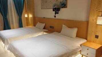 Habitación de hotel con dos camas, una mesita de noche, una lámpara de pared y un cuadro.