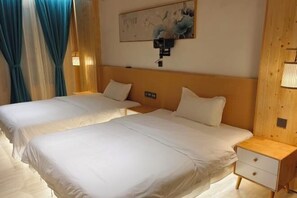 Habitación de hotel con dos camas, una mesita de noche, una lámpara de pared y un cuadro.
