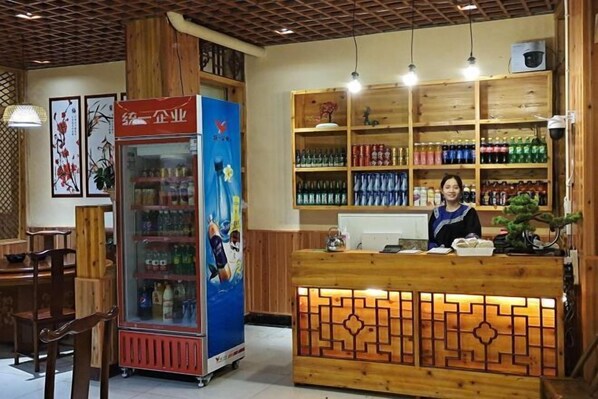A reception area with a wooden counter, a refrigerated display case, and shelves stocked with bottled beverages.