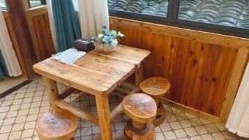 Una mesa de madera para comer con un florero, acompañada de cuatro taburetes.