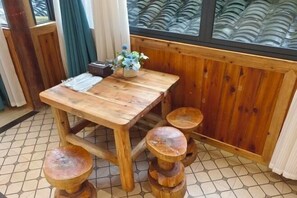 Una mesa de madera para comer con un florero, acompañada de cuatro taburetes.