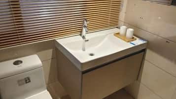 Un baño con un lavamanos blanco, un inodoro y un espejo.