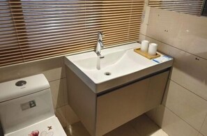 Un baño con un lavamanos blanco, un inodoro y un espejo.