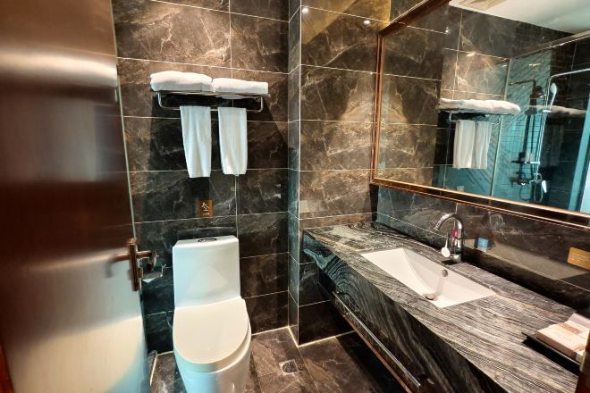 A modern bathroom with a marble sink, a glass shower enclosure, and a toilet.