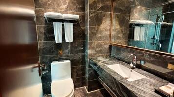 A modern bathroom with a marble sink, a glass shower enclosure, and a toilet.
