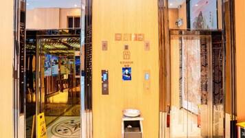 An elevator interior with a digital display, emergency phone, and a sign indicating the elevator's direction.