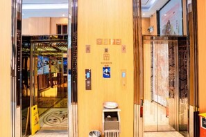 An elevator interior with a digital display, emergency phone, and a sign indicating the elevator's direction. - Chaoman Hotel (Foshan Lingnan Tiandi Pearl Sports Stadium Branch) (Foshan)