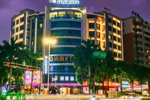 A multi-story hotel with a prominent sign at the top, multiple balconies, and a well-lit facade. - Chaoman Hotel (Foshan Lingnan Tiandi Pearl Sports Stadium Branch) (Foshan)