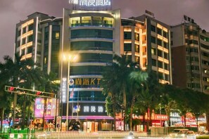 Un hotel de varios pisos con una entrada destacada, señalización iluminada y un diseño arquitectónico moderno.