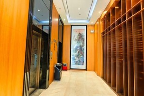 A hotel hallway with a reception desk, a large framed artwork, and a wooden panel wall. - Chaoman Hotel (Foshan Lingnan Tiandi Pearl Sports Stadium Branch) (Foshan)