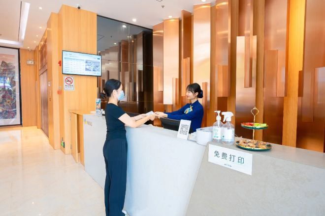 A reception desk with a digital screen, a no-smoking sign, and a sign indicating a fee for printing.