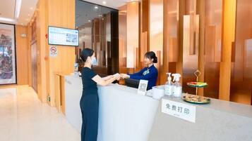 A reception desk with a digital screen, a no-smoking sign, and a sign indicating a fee for printing.