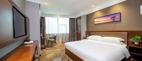Una habitación de hotel con cama, escritorio, televisor, silla y ventana.