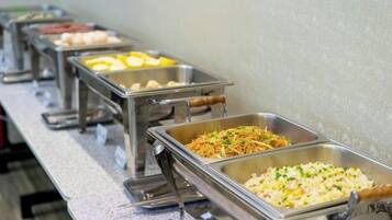Una barra de buffet con diferentes alimentos en bandejas de metal.