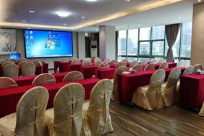 A conference room with rows of tables and chairs, a large screen, and a city view. - Chaoman Hotel (Foshan Lingnan Tiandi Pearl Sports Stadium Branch) (Foshan)