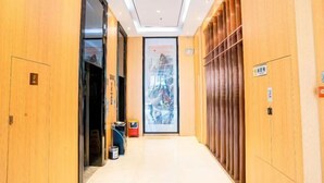 A hallway with wooden walls and a ceiling with recessed lighting. There is a door on the left and a large framed artwork on the right. - Chaoman Hotel (Foshan Lingnan Tiandi Pearl Sports Stadium Branch) (Foshan)