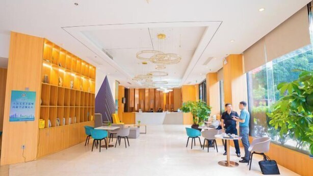 En moderne reception med en træbogreol, et receptionistskranke og et siddeområde med borde og stole.