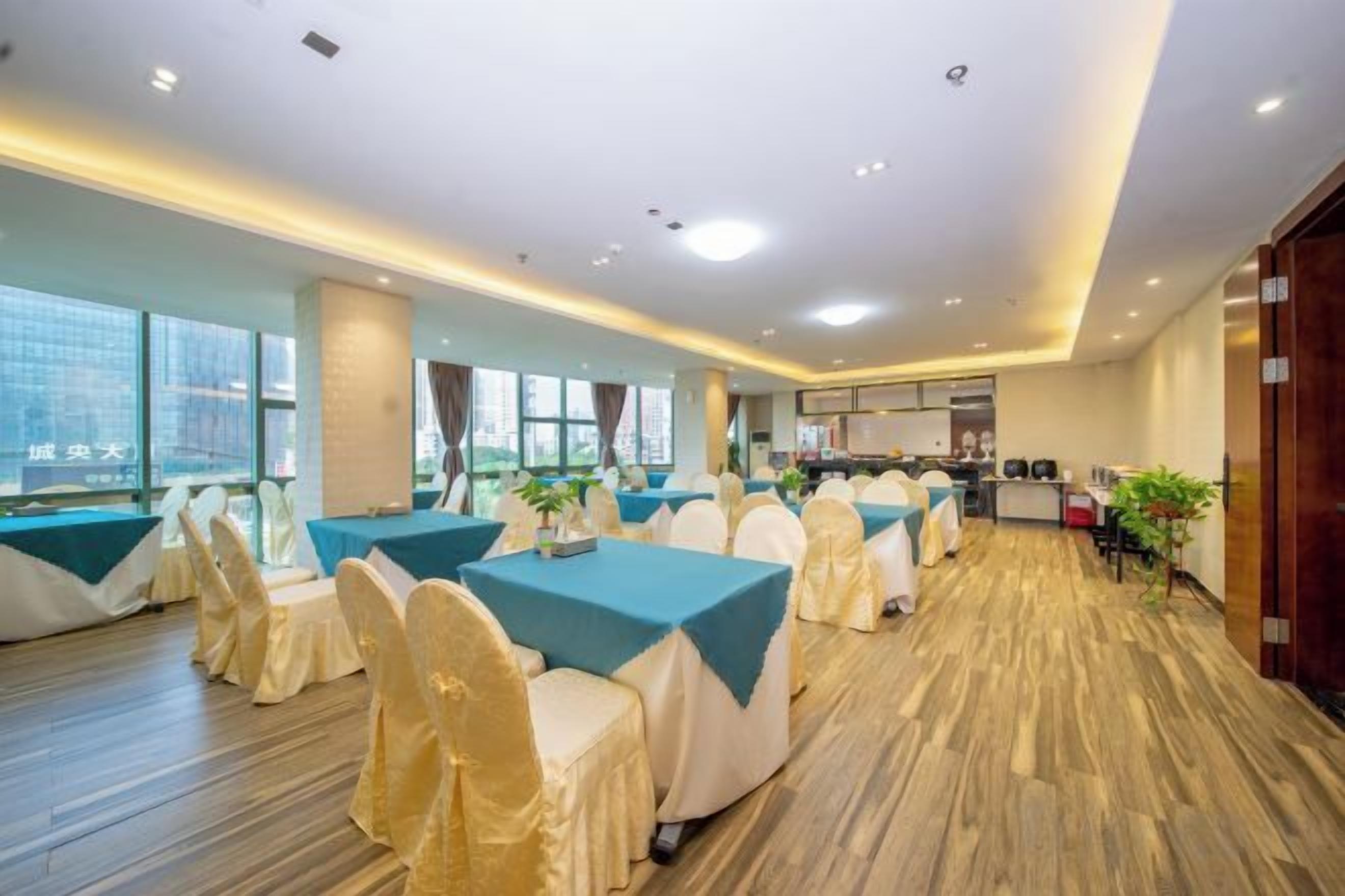 Un salón de conferencias con mesas, sillas, ventanas amplias y una zona de cocina.