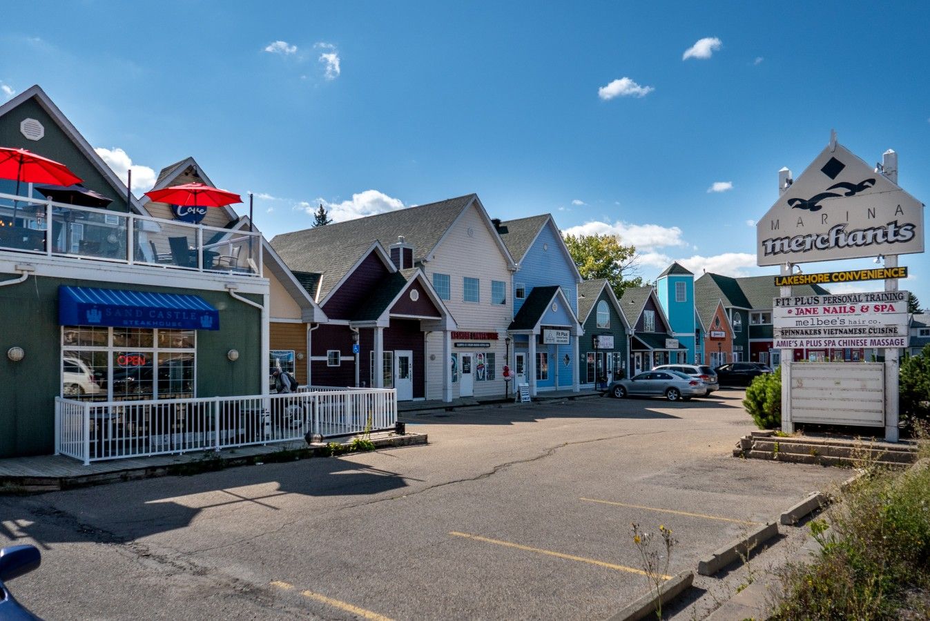 A street with various shops and a marina sign.