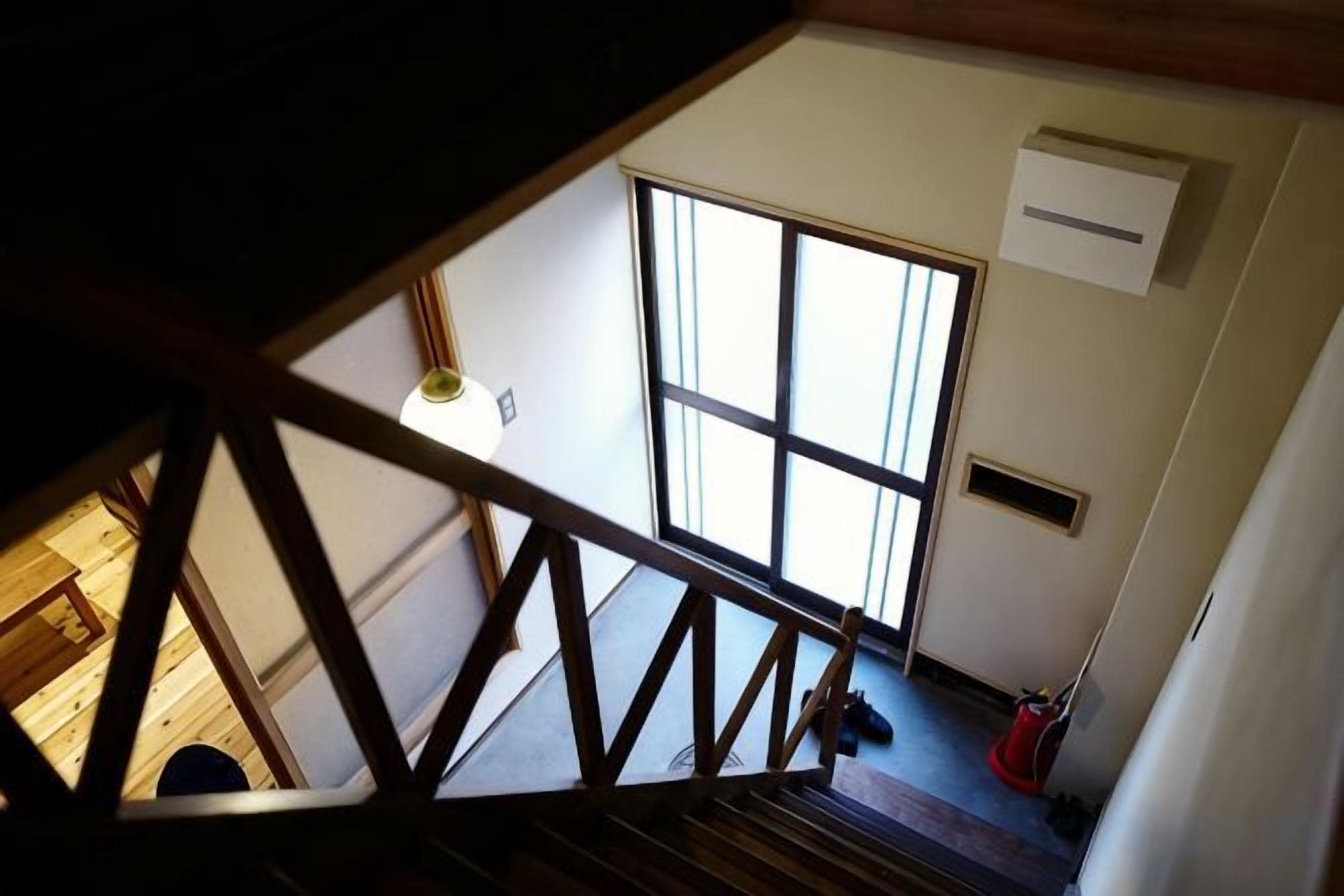 A view from a window with a wooden railing, a large window, and a ceiling light.