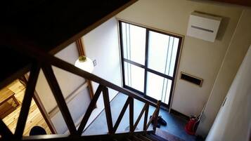 A view from a window with a wooden railing, a large window, and a ceiling light.
