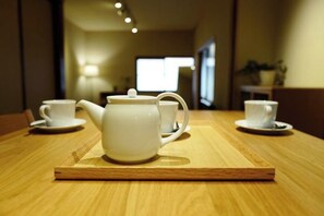 A wooden table with a teapot and two cups on a tray.