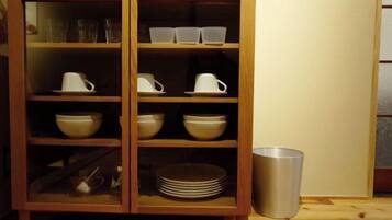 A wooden cabinet with glass doors containing bowls, cups, and plates.