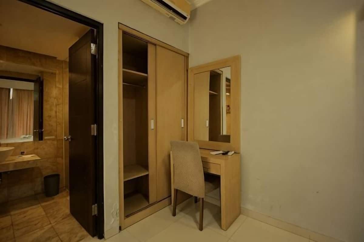 A hotel room with a bathroom, a desk, and a wardrobe.