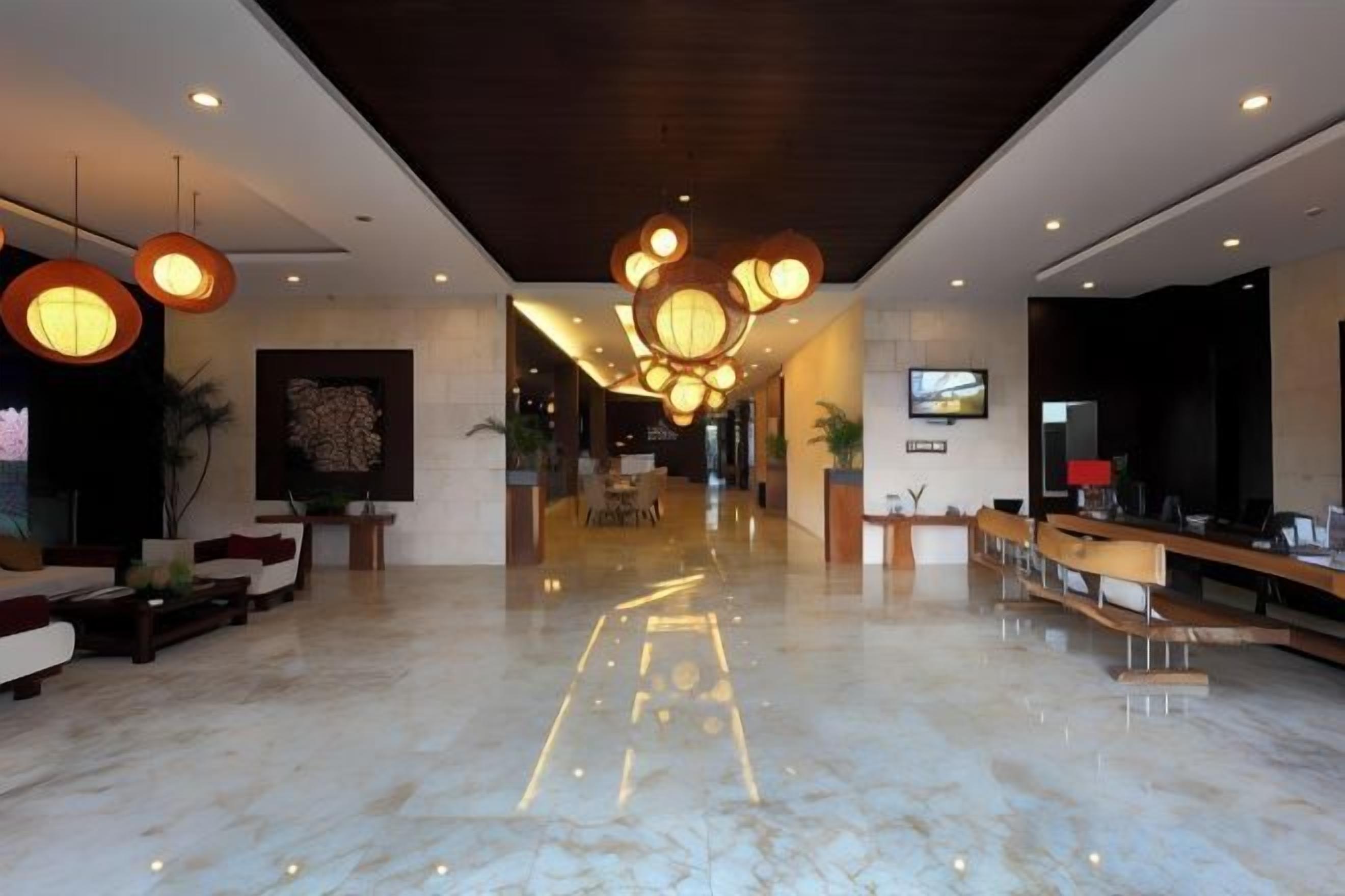 A hotel lobby with a marble floor, seating area, reception desk, and modern lighting fixtures.