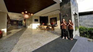 A modern lobby with a marble floor, a wooden ceiling, and a reception desk.
