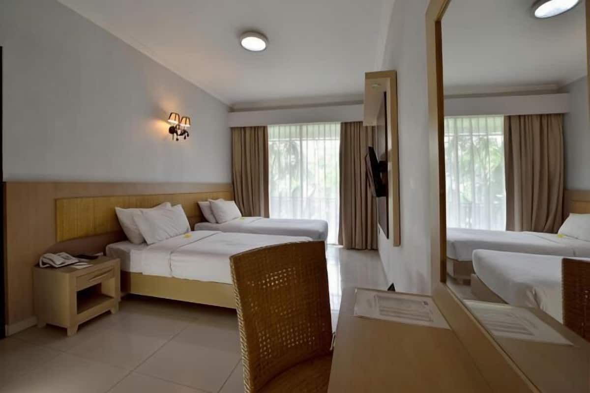 A hotel room with two beds, a desk, a chair, a nightstand, a lamp, and a mirror.