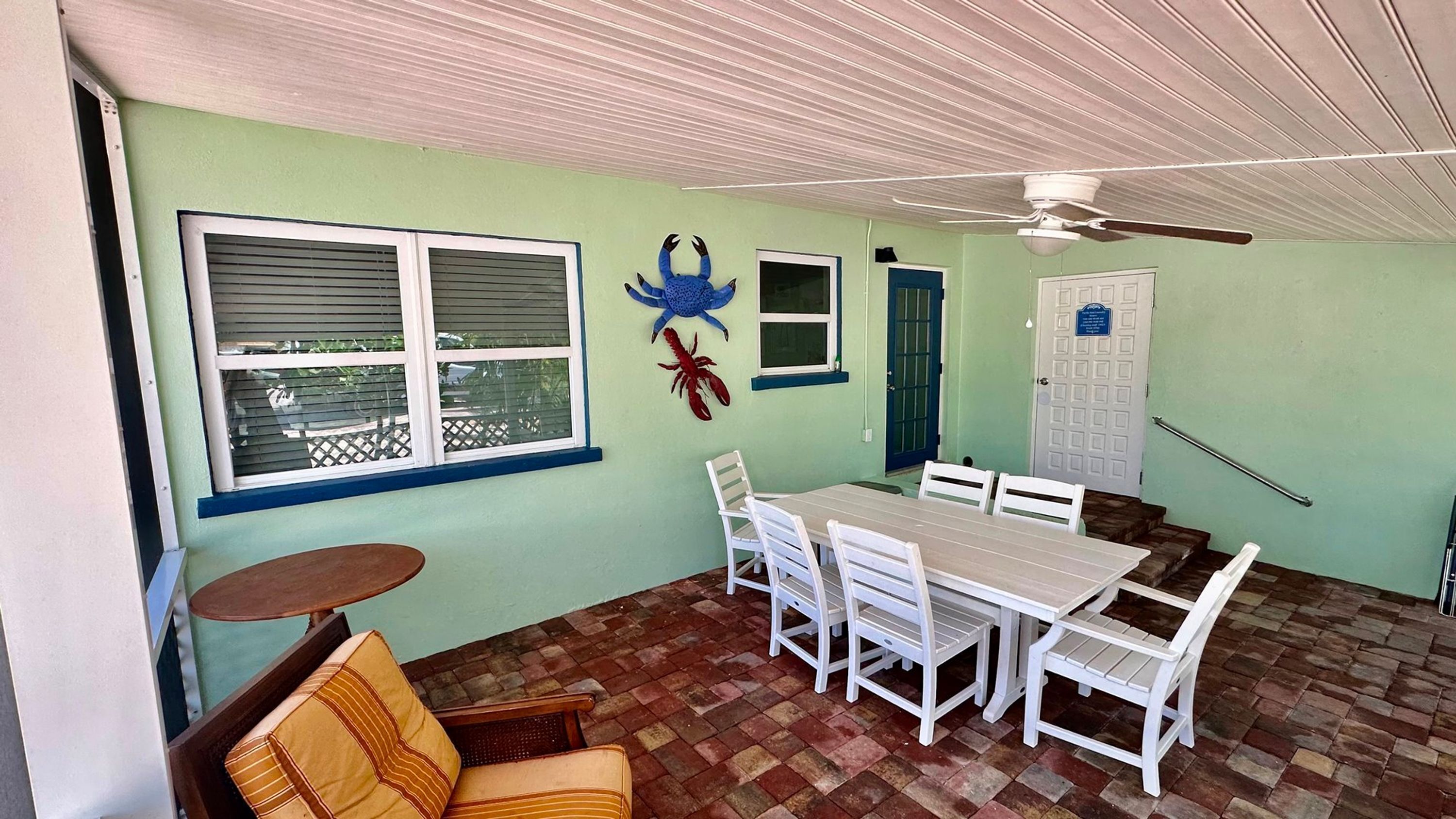 Uma área de refeições com mesa e cadeiras, um ventilador de teto e uma janela com persianas.