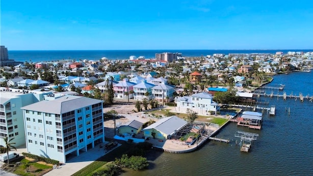 An aerial view of a coastal town with buildings along the waterfront, a marina, and a clear view of the ocean. - Seagrape Bay 205 in Fort Myers Beach (Fort Myers Beach)