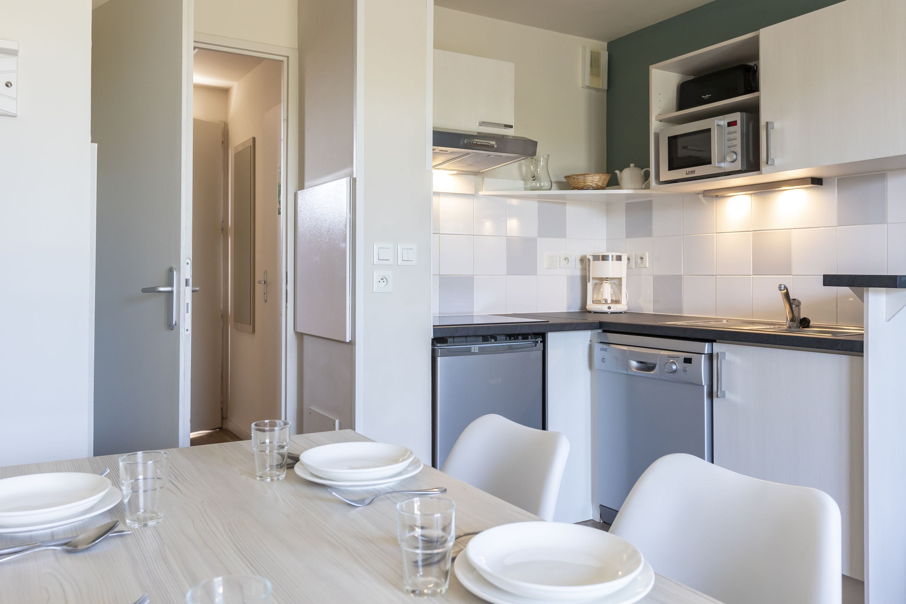 A modern kitchen with white cabinets, a dishwasher, and a microwave.