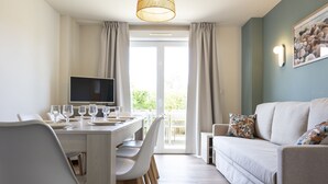 A modern living room with a dining area, a sofa, and a TV. - Residence Les Villas De La Baie (Le Crotoy)