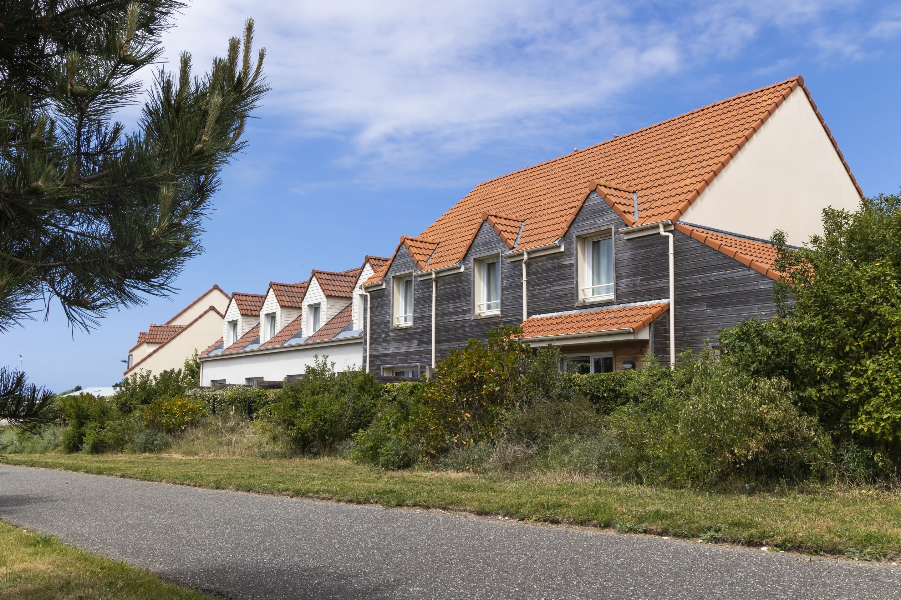 Een rij moderne huizen met schuine daken en een verharde oprit.