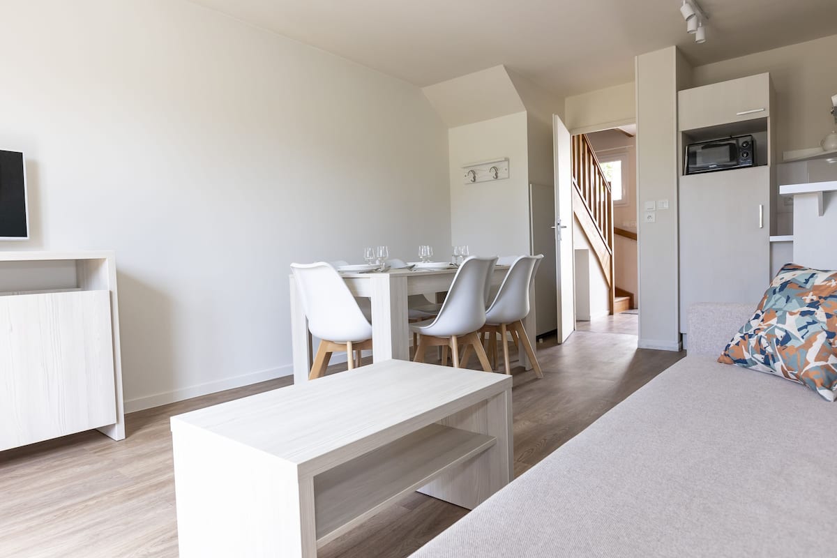 Un salon moderne comprenant un canapé, une table basse et un coin repas avec des chaises et une table.