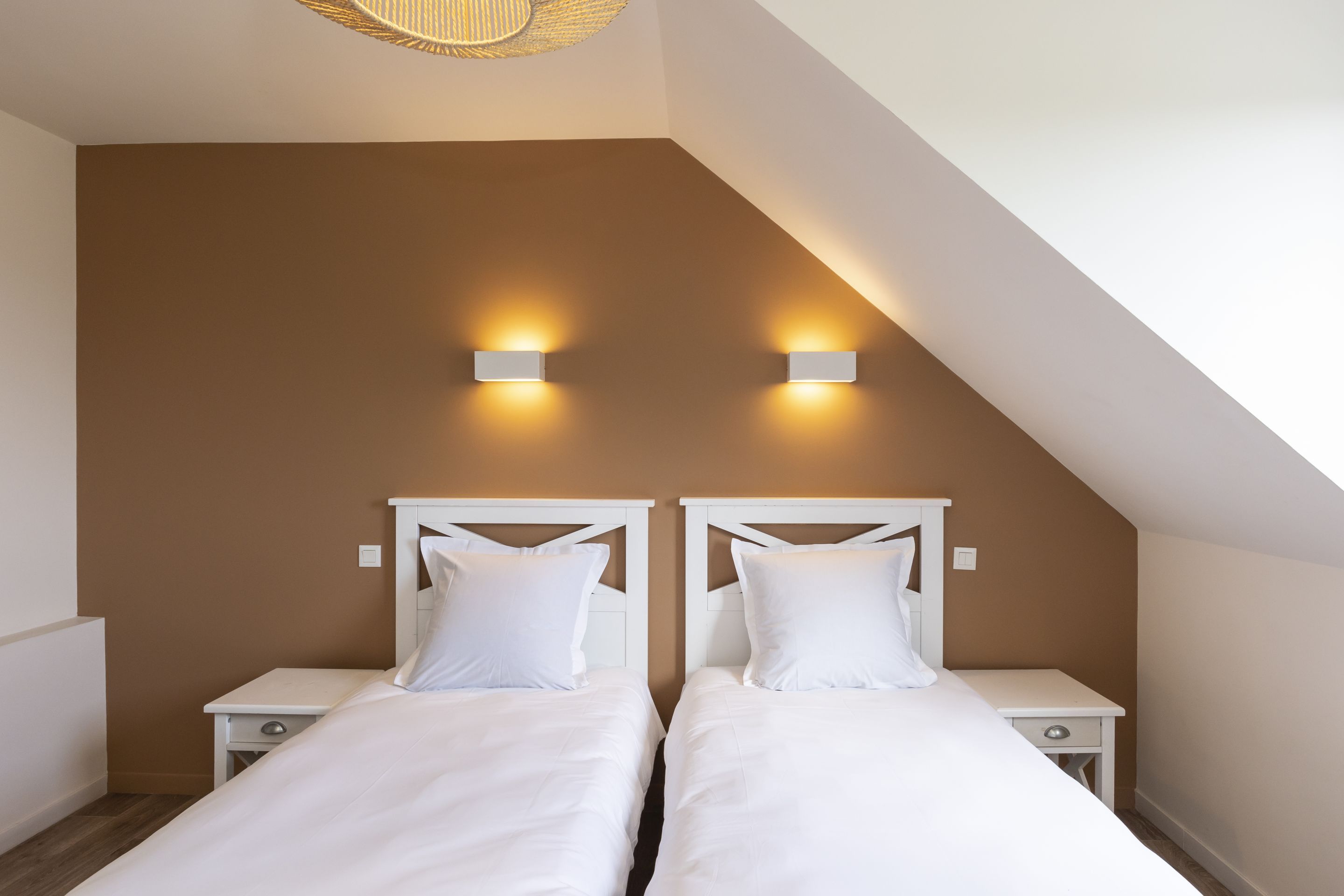 Une chambre à coucher avec deux lits, des têtes de lit blanches et des tables de chevet.