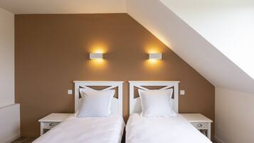 Une chambre à coucher avec deux lits, des têtes de lit blanches et des tables de chevet.